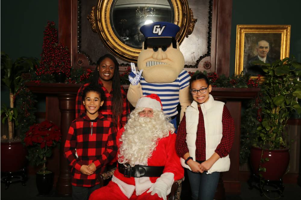 Santa and Louie posing with alumni family of three
